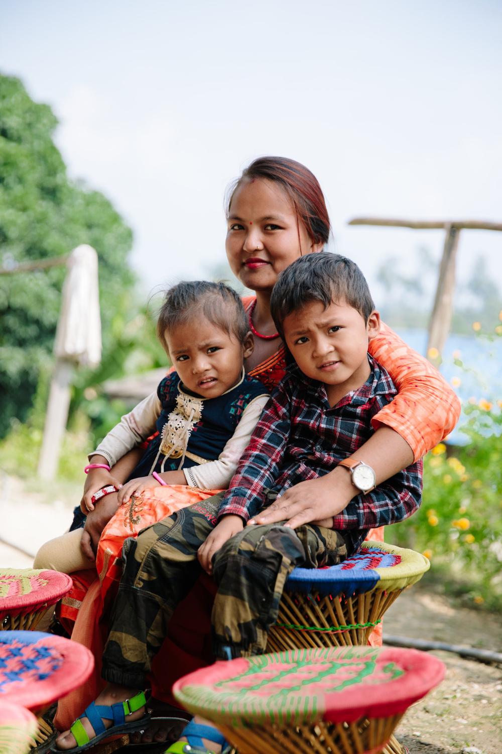 Nepalilainen äiti kaksi lasta sylissään.