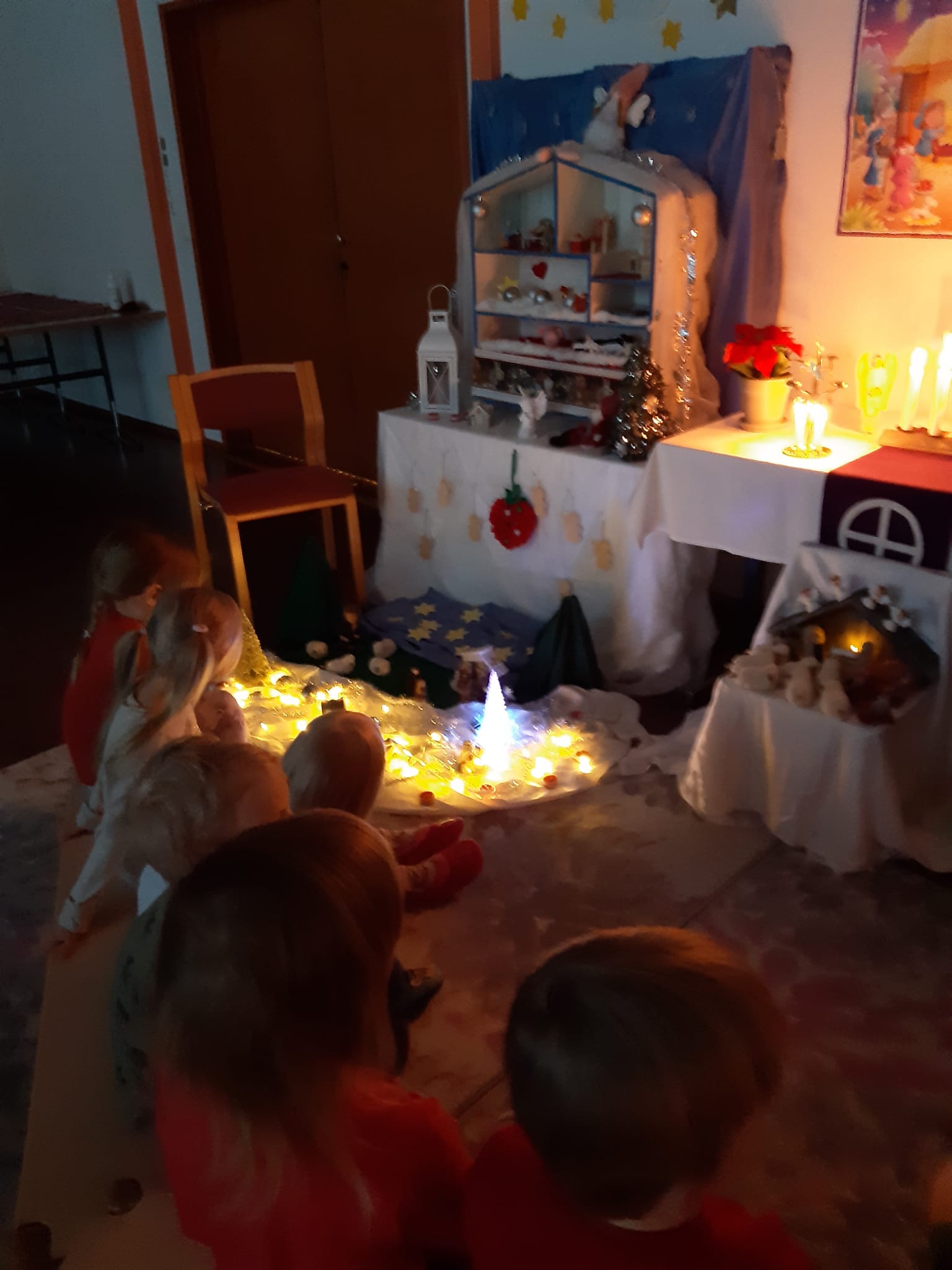 Päiväekrholaiset istuvat jouluisessa kerhon kynttilähetkessä, lattialla kuvattu tavaroilla joulun kertomus