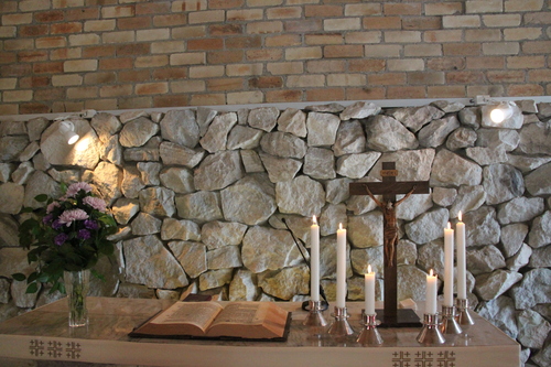Virtasalmen kirkon alttari, jossa risti, kynttilät ja kukkia.